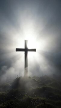 Silhouette of a dark christian cross standing in a thick morning fog with bright white light glowing from behind the structure