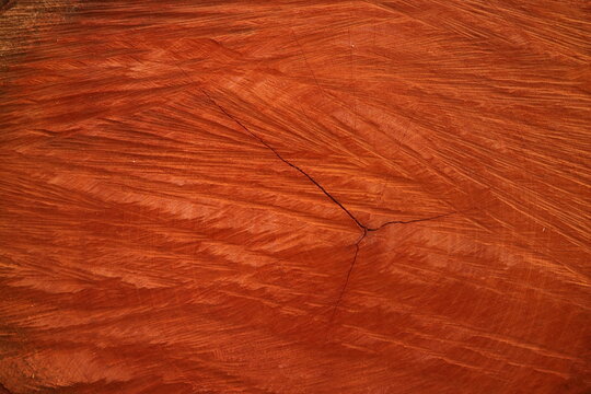 Rough cut reddish brown wood texture background with natural grain patterns and circular saw marks on a hardwood lumber stump surface