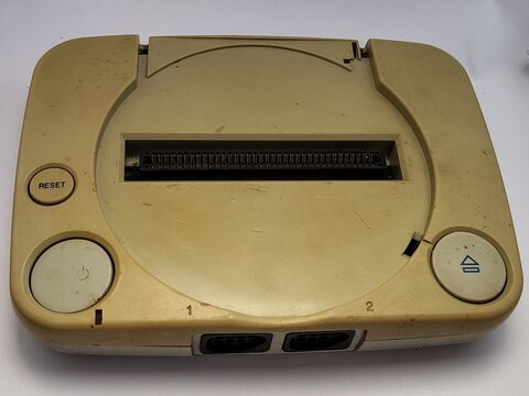 Top view of a dusty, yellowed retro 8-bit game console clone featuring power, reset, and eject buttons with a central cartridge slot
