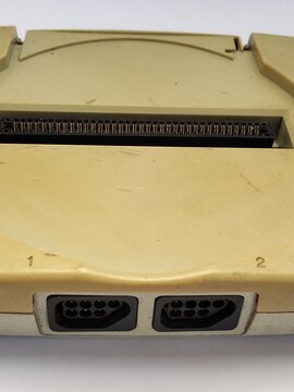 Close-up of 9-pin controller ports and the cartridge slot on a dusty, yellowed retro 8-bit famiclone video game console