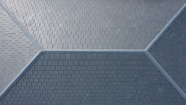 Top down overhead view of perfectly installed grey slate shingles showing clean geometric lines and precise ridge capping.
