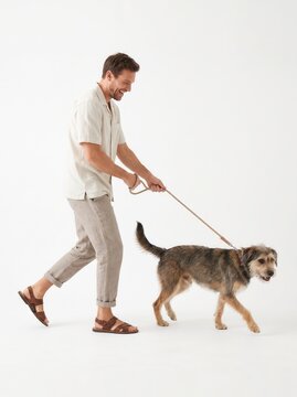 Smiling man walking his cute mixed-breed dog on a leash against a white background123