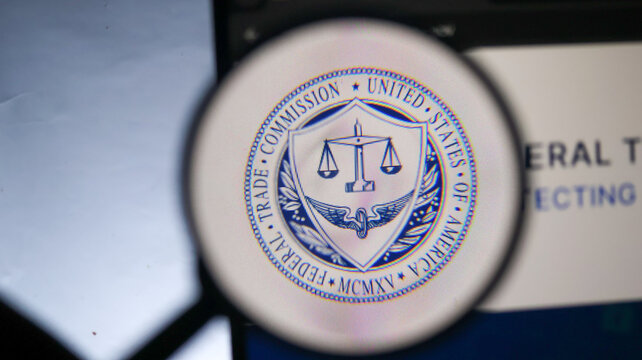 Federal trade commission circular emblem printed on screen viewed through magnifying glass with blue white color scheme.