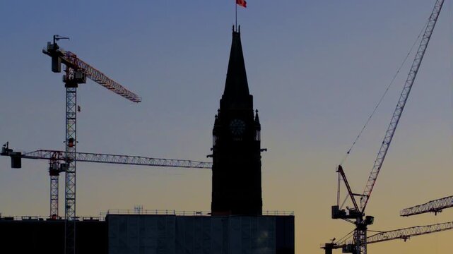 Ottawa, Ontario, Canada - October 7, 2026: Silhouette of construction cranes surrounding the Peace Tower on Parliament Hill at dusk