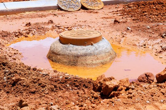 Construction site shows manhole cover surrounded by muddy water