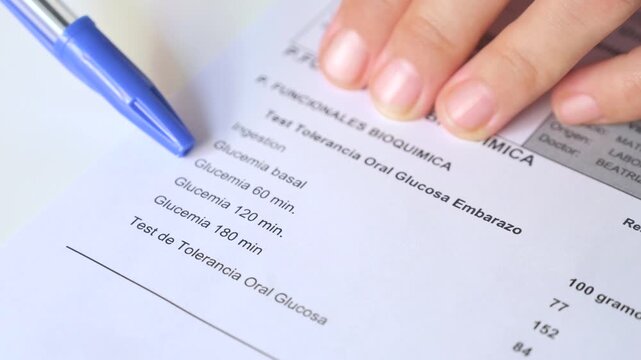 Close up of a patient's hand checking medical results for gestational diabetes on a white background