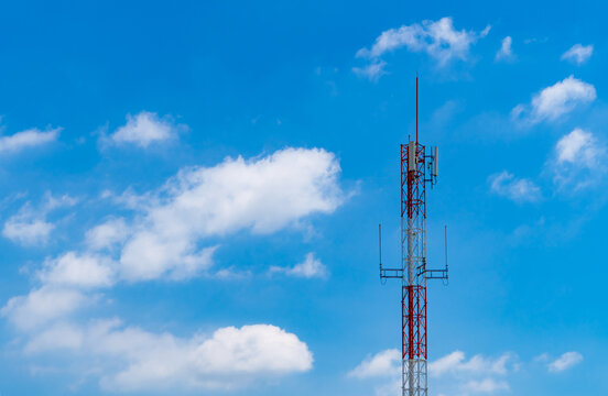 Telecommunication tower with cellular antennas against blue sky and white clouds, supporting wireless communication, mobile connectivity, data transmission and modern telecom network infrastructure.