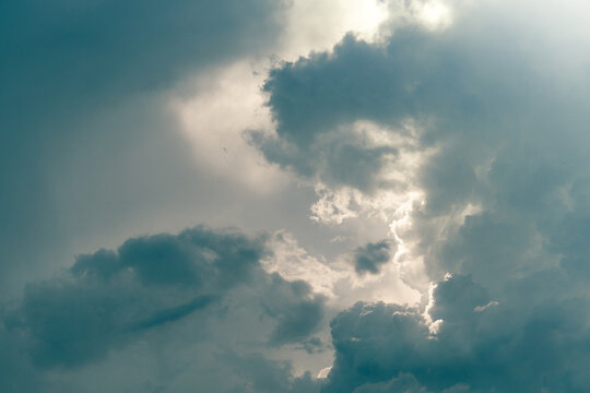 Dramatic storm clouds gather across the sky as bright sunlight breaks through dense cloud layers. Luminous rays and atmospheric contrast for weather, climate, nature and dramatic background themes.