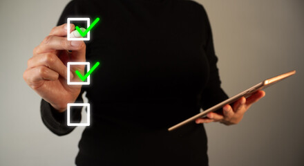 Hand marks checkmarks on checklist. Person holds tablet and gestures. Represents task completion or progress tracking. Suitable for business, productivity, or goal achievement themes © Gabriela