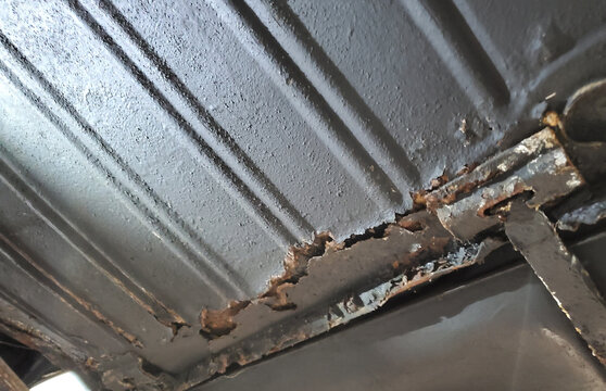 Rusted seam on a car floor pan, corroded metal on the underside of an old vehicle