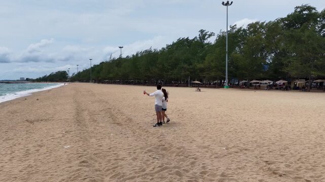 Young Couple Walking Hand in Hand and Taking Selfie on Sandy Beach