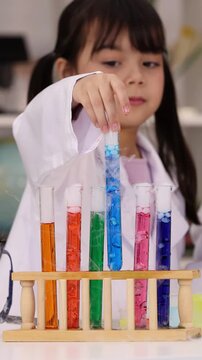 Little Girl in Lab Coat Examining Colorful Chemical Test Tubes