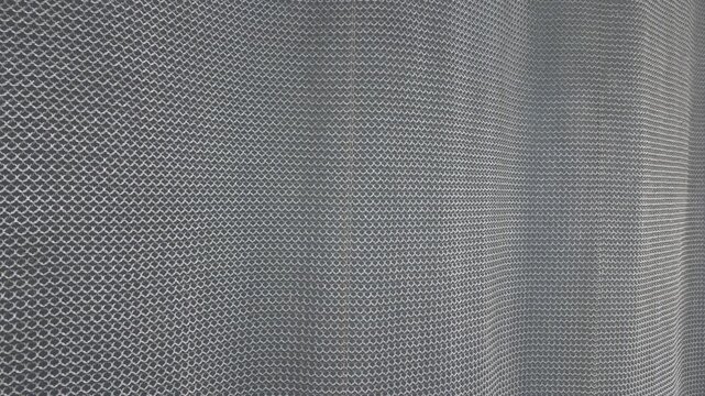 Close-up abstract view of a metallic chain mesh surface forming a repeating circular pattern, creating a modern industrial texture and geometric background.