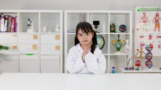 Young Girl in Lab Coat Sitting at Desk in Science Classroom
