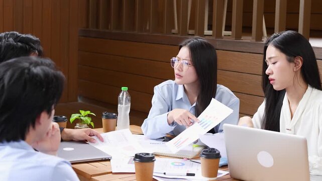 Asian Business Professionals Discussing Financial Reports in Modern Bangkok Office