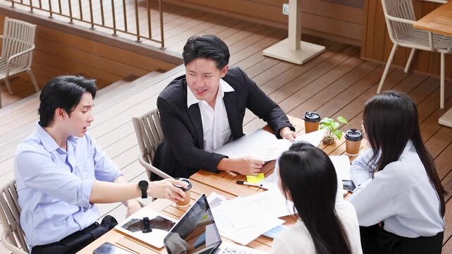 Asian Business Professionals Discussing Financial Reports at Outdoor Cafe Table