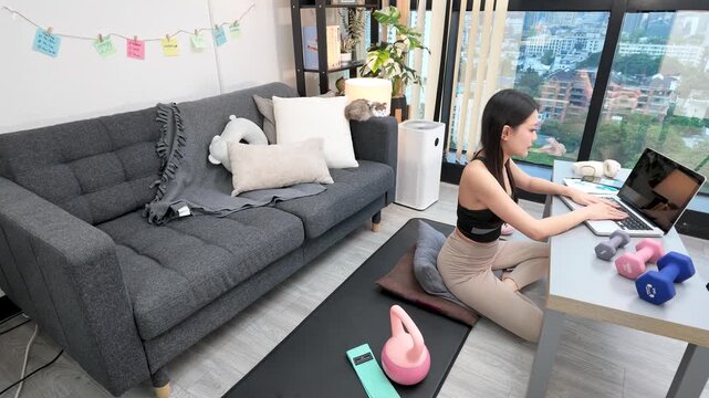 Asian Woman in Sportswear Working on Laptop in Modern Living Room