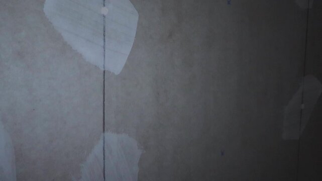 Detailed vertical pan of a new plasterboard or drywall partition with screw heads covered in white putty, showing the preparation phase before painting during a home renovation or construction