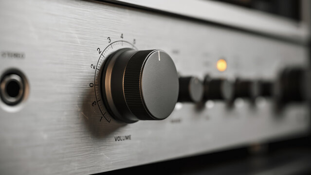 Macro close up of a black volume control knob on a brushed metal audio amplifier receiver with receiver front panel detailed close metallic audio electronics texture