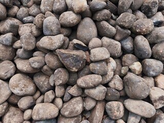 Pile of smooth natural river stones and grey pebbles creating a textured mineral background. © Dani