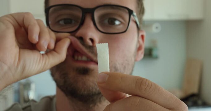 Close-up of a man placing a nicotine pouch under his upper lip, representing smokeless nicotine use, oral products and consumption habits.