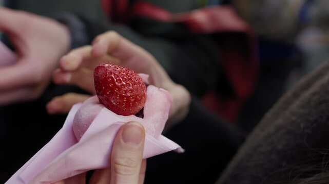 Ichigo daifuku, a Japanese confection of soft glutinous rice cake around a whole strawberry, served in a paper wrapper