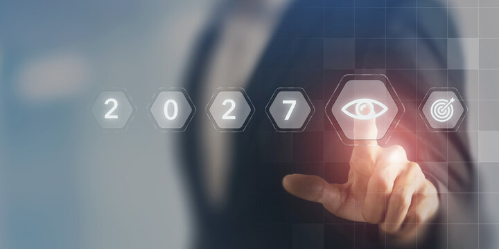2027 Business Outlook, Future Vision and Strategic Goals. Touching a digital eye icon beside 2027 and target symbols on a futuristic interface. Business outlook, vision, strategy and future goals.