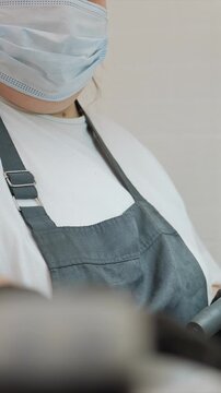 Close up of beauty professional in mask and apron holding tools for pedicure or manicure. Gloved hands indicate hygiene focused service treatment nail