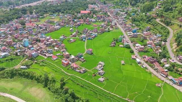 Drone view of damaged buildings on an eroded riverbank beside swirling flood mud and sediment after a flash flood in a Nepali town