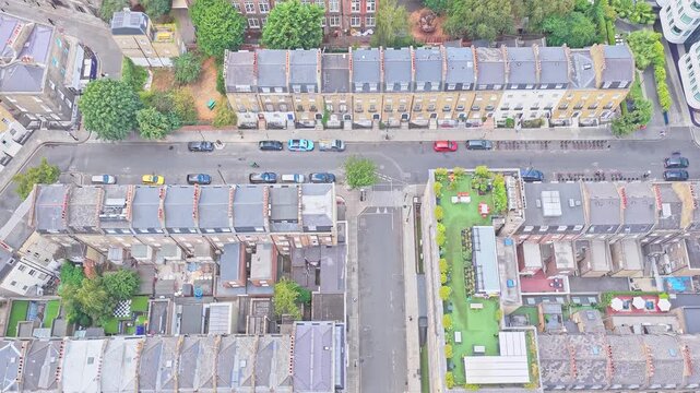 Overhead view of Victorian and Georgian terraced housing, residential street, landscaped garden, parked cars and dense urban blocks in the King's Cross area, drone descent.