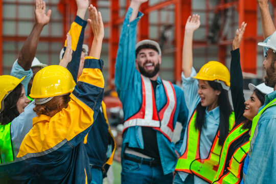 Happy diverse factory workers giving high fives and cheering together to celebrate success