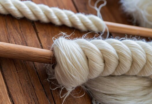 Close-up of creamy white twisted rope and yarn on rustic wooden surface