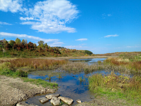 Autumn rural landscape with river and blue sky.