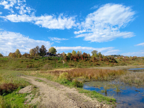 Autumn rural landscape with river and blue sky.