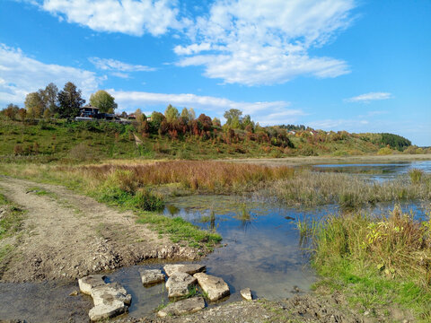 Autumn rural landscape with dirt road and swampy river