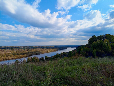 Beautiful landscape with river and blue sky with clouds in autumn.