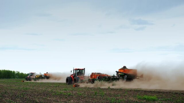 Professional agricultural machinery with powerful tractors and seed drills operating in a cultivated field. Modern mechanized crop production and large-scale farming technology during planting season.