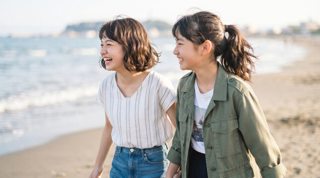 海辺を笑顔で歩く若い女性の友人同士