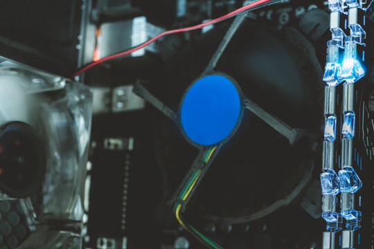 Computer cooling fan with dust on its frame beside illuminated memory modules and a second fan inside a desktop case, visible motherboard components, heatsink fins and wiring for hardware maintenance.