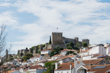 Medieval hilltop castle with crenellated walls and a square keep rises above whitewashed houses with terracotta roofs in Montemor o Velho, Portugal. Heritage tourism and cultural travel destination. © Renata