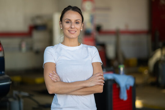 Confident female mechanic standing with crossed arms in garage