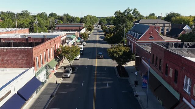 Low view along a main street of red brick storefronts with blue awnings, street trees and a red brick corner building with dormer windows in Bennettsville, South Carolina, USA. Aerial view