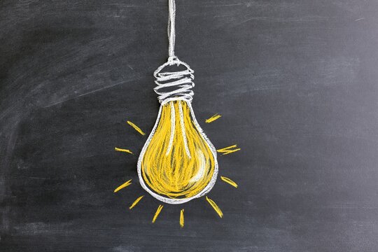 The lightbulb glowing on chalkboard symbolizing bright idea and creativity