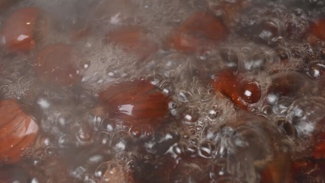 sweet chestnuts boiling in bubbling hot water being stirred 