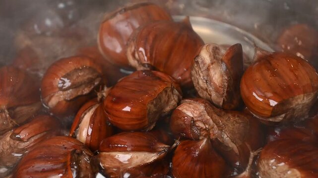sweet chestnuts boiling in bubbling hot water being stirred 