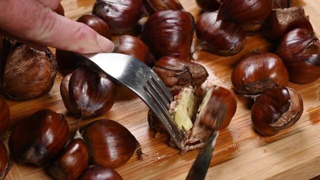 cutting open a boiled sweet chestnut on a wooden cutting board