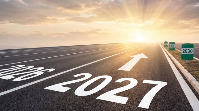 Business year 2027 concept photo. Asphalt highway stretching towards a bright sunrise with year numbers painted on the road and milestone markers