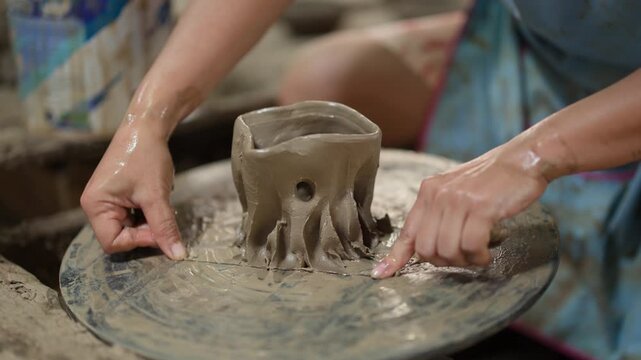 Asian Artisan Cutting Clay from Pottery Wheel in Traditional Workshop