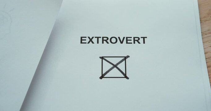 Close-up of a person marking an &ldquo;Extrovert&rdquo; checkbox with a pen, representing personality traits, sociability, outgoing behavior and self-assessment.