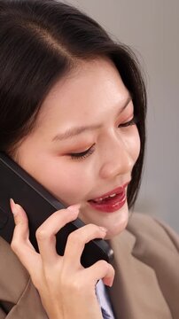 Asian Businesswoman Smiling While Talking on Smartphone in Office